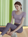 Lilac cropped short sleeve women fitness coord seated fullbody studio wearing view, OEM custom two-piece training outfit Haideyu factory